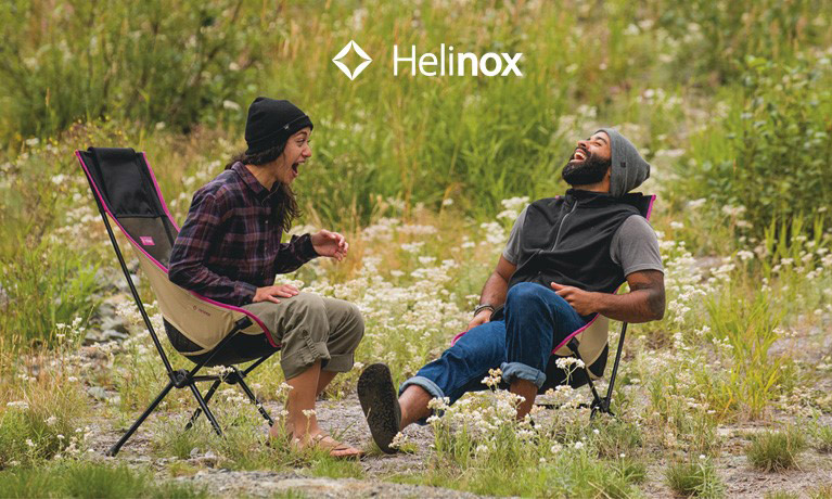 two campers sitting on helinox chairs laughing